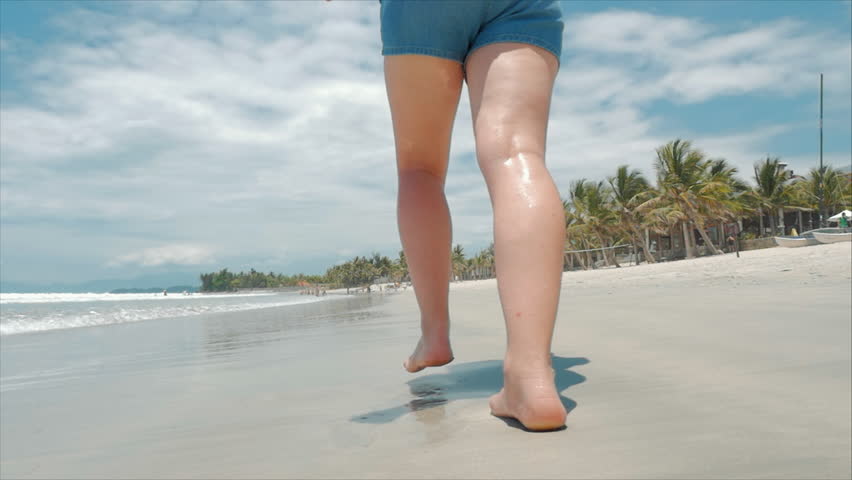 European Beautiful Brunette in Black Glasses, White-shirt and Blue Shorts Goes Under the Hot Summer Sun Along the Tropical Exotic Coast of Vietnam, Carefree Girl Running on the Sand Right to the Ocean