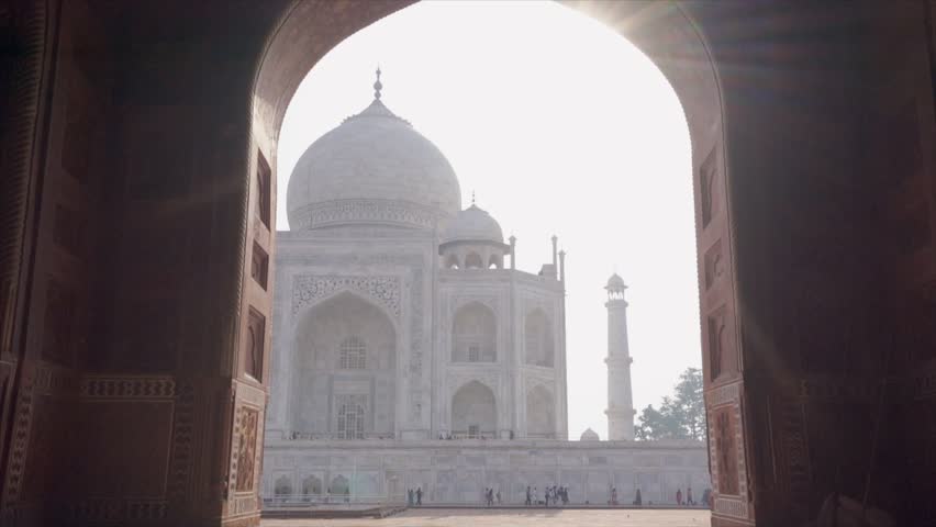 SLOW MOTION- Rear view of young woman running towards the Taj Mahal at sunrise reaching temple entrance. Girl wandering and discovering India