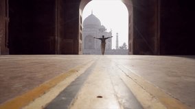 Young man arms outstretched at the famous Taj Mahal at sunrise- freedom and positive emotions, Agra, India. People travel Asia concept