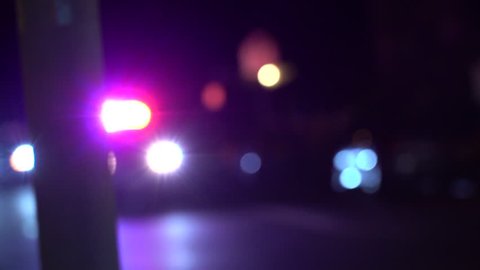 A Police Car Drives Past At Night With Bright Bokeh Lights.