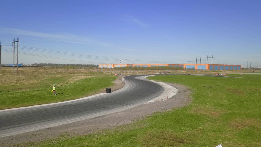 Green racing car drifting on a track with smoking tires and skid marks on an asphalt
