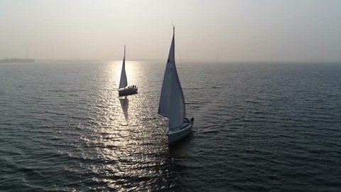 Aerial view of two sloops at sundown are sailing boats with single mast and fore-and-aft rig plus one head-sail the most common setup of modern sailboats is the Bermuda-rigged configuration 4k quality