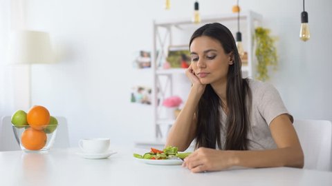 Dissatisfied woman looking on salad, healthy low-calorie diet for weight loss
