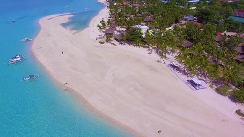 Aerial - drone flying over idyllic peaceful tropical sea with turquoise water, white sand beach, palm trees. Resort town of Bantayan Island, Cebu, Philippines. Tourism.