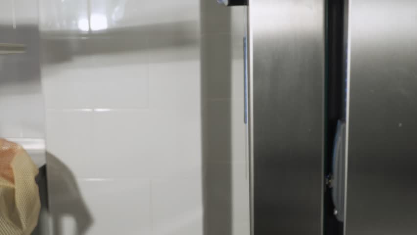 Baker puts on cinnamon rolls on a baking sheet in the oven to bake. Side view, hands close-up.