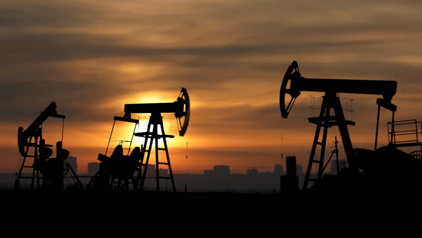 working oil pumps silhouette against sunrise