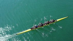 Aerial drone bird's eye view video of yellow sport canoe operated by team of young team in emerald clear sea