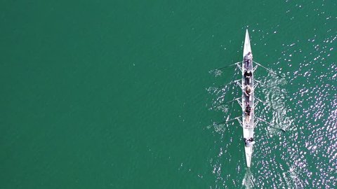 Aerial drone bird's eye view video of sport canoe operated by team of young men and women in open ocean sea