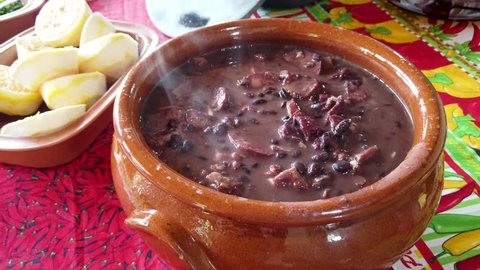 Tradicional brazilian feijoada pan served in a clay pot with smoke, stable  close up