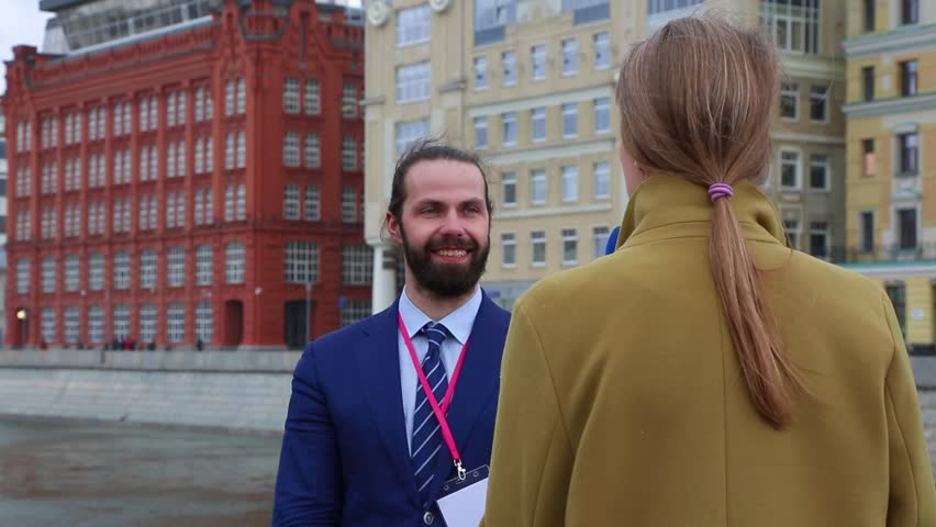 young attractive female journalist is interviewing a young businessman in the city. Young woman working as media TV reporter with business man.