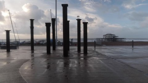 BRIGHTON, ENGLAND - DECEMBER 7, 2018.  Brighton beach in East Sussex on a windy, stormy day. Looking at the West Pier from the back of the beach front as pedestrians walk through the wind