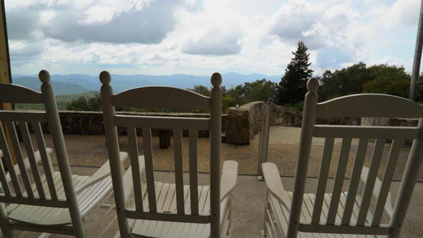 A peaceful, serene, scene of rustic, white rocking chairs on a deck overlooking the Appalachian mountain peaks at Brasstown Bald, Georgia.