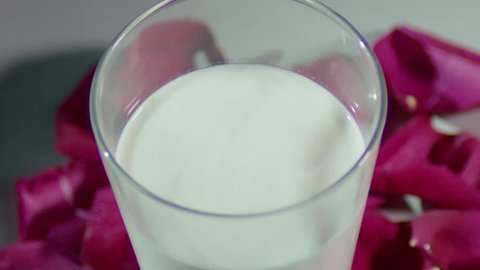 Closeup shot of Adding dry fruits(Cardamom,almonds and pistachios)into glass of milk. thandai making in process. cinematic ad shot of putting dry fruits into milk. 