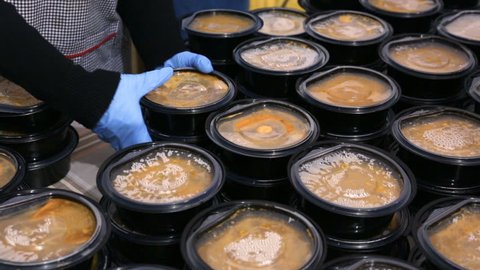 Warm soups in black plastic dishes in a kitchen for poor and homeless people.