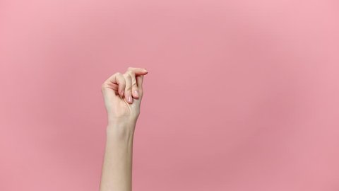 Woman hand snaps her fingers to rhythm, showing thumbs up gesture isolated over pastel pink background in studio. Copy space for advertisement. With place for text or image. Advertising area, mock up.