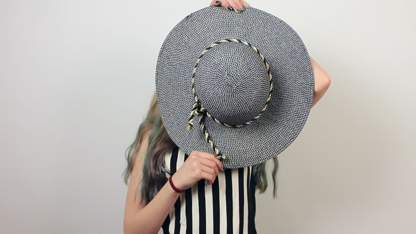 Funny beautiful girl with hat and fake moustache having fun. Positive girl on grey background.