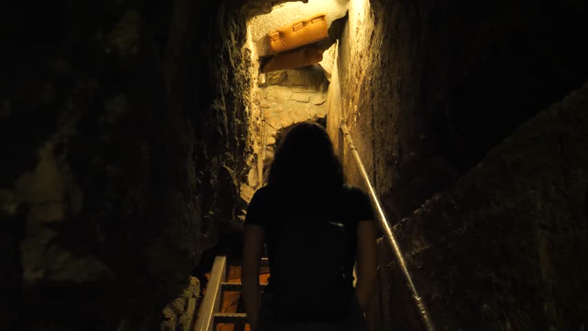Young unrecognizable female tourist climbing stairs at Western Wall tunnels