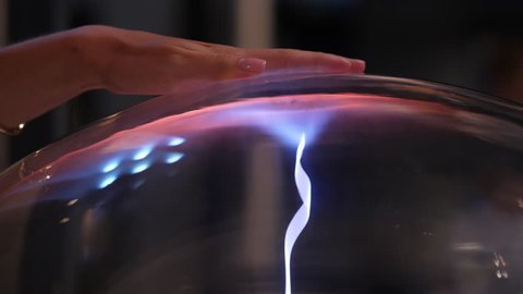Woman hand lying on top of plasma sphere, lively blue stream touching arm from inside. Girl take out palm and flow dissolve, change to many thin filaments around ball