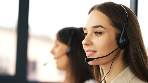 4K. Office call center work. Two young smiling women operators answer client 