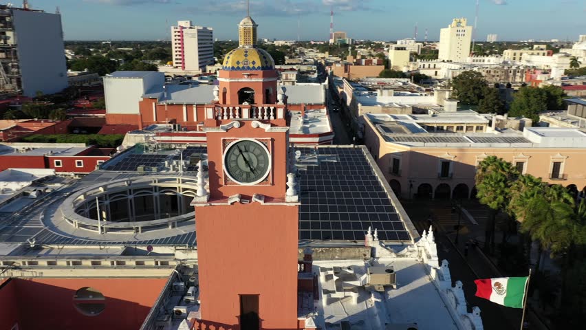 Aerial camera doing a close orbit of the clock tower above the municipal building on the Grand Plaza in Merida, Yucatan, Mexico at sunset.