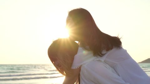 Young Asian LGBT friends playing on beach, beautiful women friends feel happy and fun relax playing on beach near sea sunset in evening. Lifestyle lesbian friendship travel on beach. Slow motion shot.