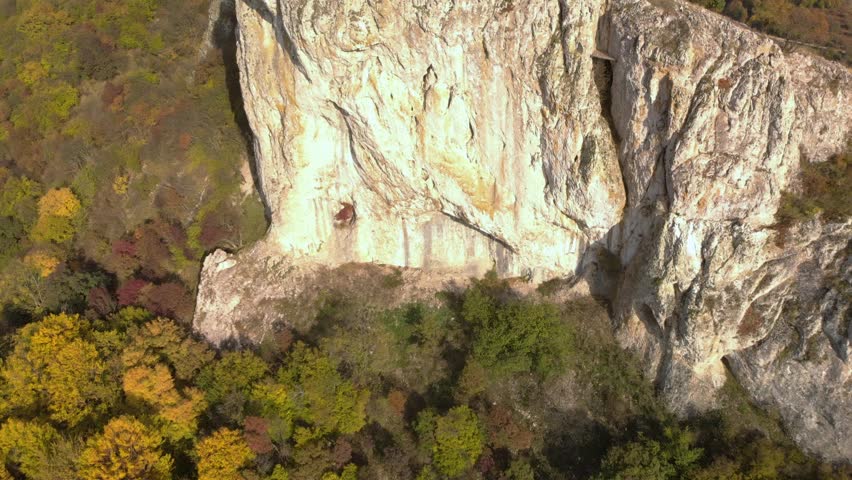 Aerial panning high angle shot of big high rock on the edge of a mountain