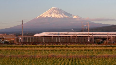 Mount Fuji, Shizuoka, Honshu, Japan - CIRCA 2017: Shinkansen Bullet Train passing through harvested rice fields below the snow capped volcano