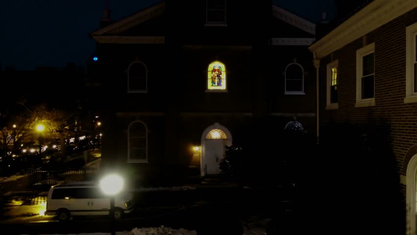 Aerial nighttime tilt up from the street level of the Holy Trinity Lutheran Church to the steeple Lancaster Pennsylvania Concept: traffic, urban, downtown, cars, trucks, lights, rat race, ?church,