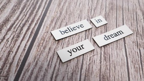 The words BELIEVE IN YOUR DREAM on a table with the camera turning around them.
