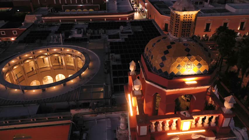 Aerial camera very close to the clock tower at night and ascending from the Municipal Building at night in Merida, Yucatan, Mexico.
