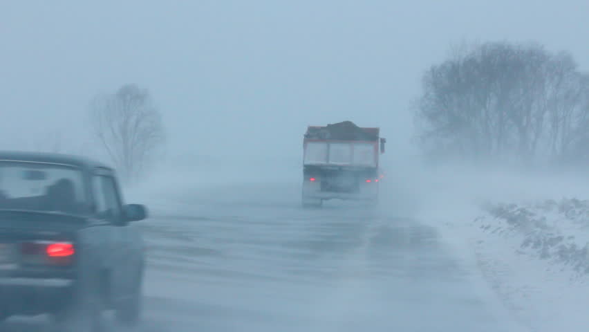 cars on winter road in blizzard