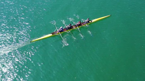 Aerial drone bird's eye view video of sport canoe operated by team of young women in emerald sea