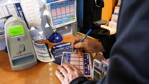 Paris, France - 29 Mar 2019: Newsworthy sunlight flare over senior male hands marking numbers on EuroMillions ticket inside Tabaco press kiosk hoping to win the big jackpot of 10000000 millions euros