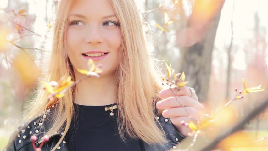 
Gorgeous young woman with golden hair playing among blooming trees