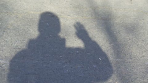 Hi, hello, man waving hand, welcome. Hand waving, saying goodbye. Shadow man's over asphalt. Bye bye.