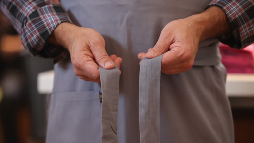 Hands tying an grey apron around the waist front view. Preparing and cooking food with friends. | Shutterstock HD Video #1027257041