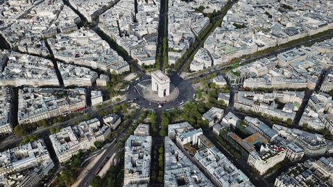 Aerial, orbit, drone shot, of traffic around Arc de Triomphe, on Place Charles De Gaulle, in the cityscape of Paris, on a sunny, summer day, in France