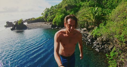 POV shot of young man jumping into pristine blue water in tropical jungle, man does backflip, influencer lifestyle, amazing vacation