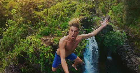POV shot of young adventurous man cliff jumping off of amazing jungle waterfall, tropical vacation lifestyle