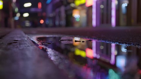 Man stepping into muddy puddle at night time in neon lit street Reeperbahn Hamburg St Pauli Grosse Freiheit Germany Red Light District Nightlife