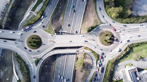 Highway interchange junction with traffic aerial top down view footage from drone with vehicles driving on freeway, roundabout and ramp lanes, 4K video of transportation from above
