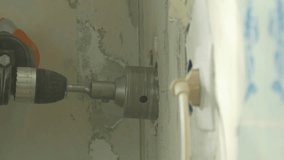 Ungraded: Worker drills a hole in the wall for an electrical outlet with a drill with a crown. Ungraded H.264 from camera without re-encoding.