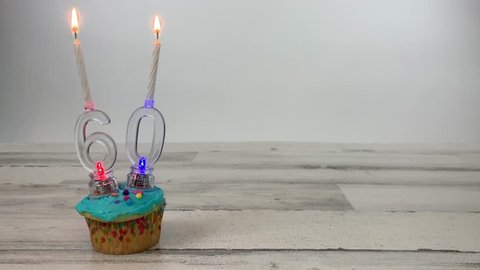 60th birthday candles on a cupcake with LED flashing lights on a wood table with copy space