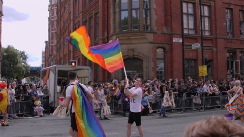 Man Waving Rainbow Flag at LGBTQ, Lesbian, Gay, Bisexual, Transgendered, Queer, Pride Parade Street Party Celebration Marching in slow motion