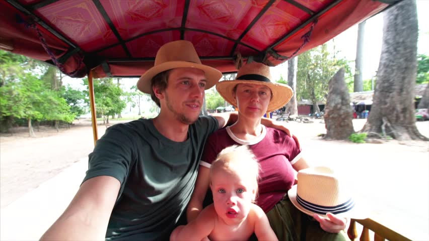 Slow motion selfie of family driving by tuk-tuk taxi service at Angkor Wat, a temple complex in Cambodia, one of the largest religious monuments in the world.