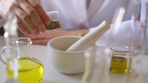 the scientist  doctor is making natural  herb medicine or cosmetic in the laboratory. pour  herbal  in the mortar . on table with  organic essential oil . skincare health product industry .closeup