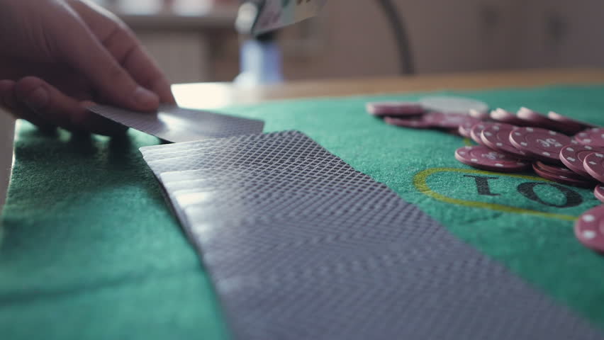 Casino: Dealer shuffles the poker cards on the table. Hands close-up. Casino gamble.
