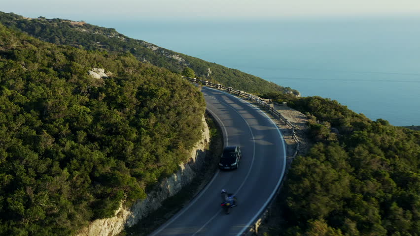 Aerial view; drone flight over the winding mountain road; dangerous highland route with moving fast cars, motorcycles and bicycles; sunny evening sunset in Portugal, beautiful winter forest; Royalty-Free Stock Footage #1027286093