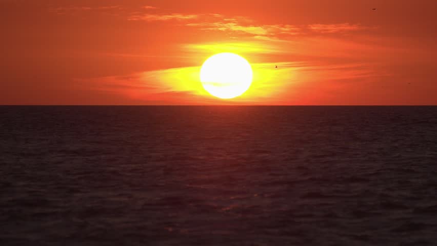Slow Motion shot of Orange Florida Sunset over the Gulf of Mexico with sea birds flying in the distance