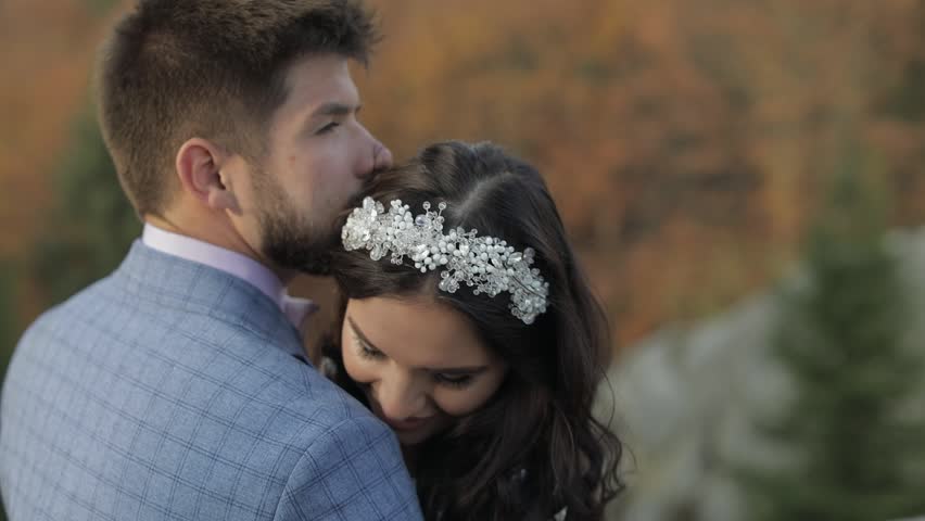Groom with bride on a mountain hills in the forest. Wedding couple. Happy family. Man and woman in love. Lovely groom and bride. Wedding day. Slow motion